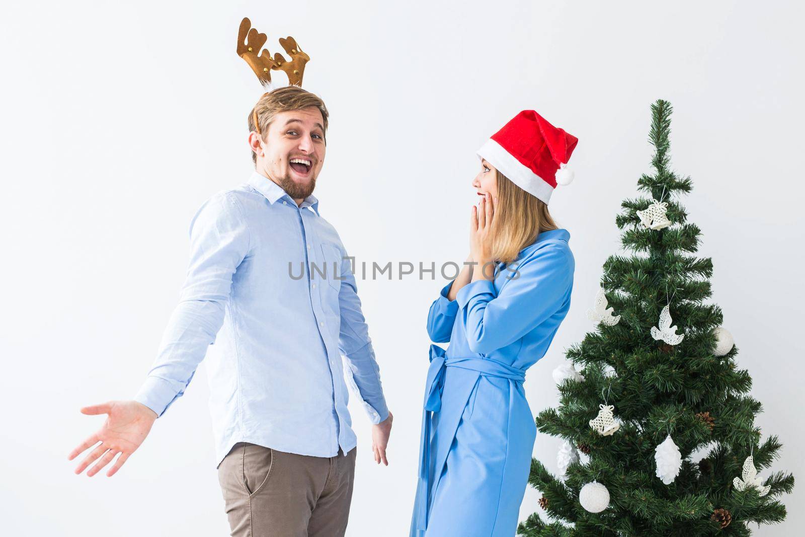 Holidays and celebration concept - Young funny couple celebrating Christmas at home by Satura86