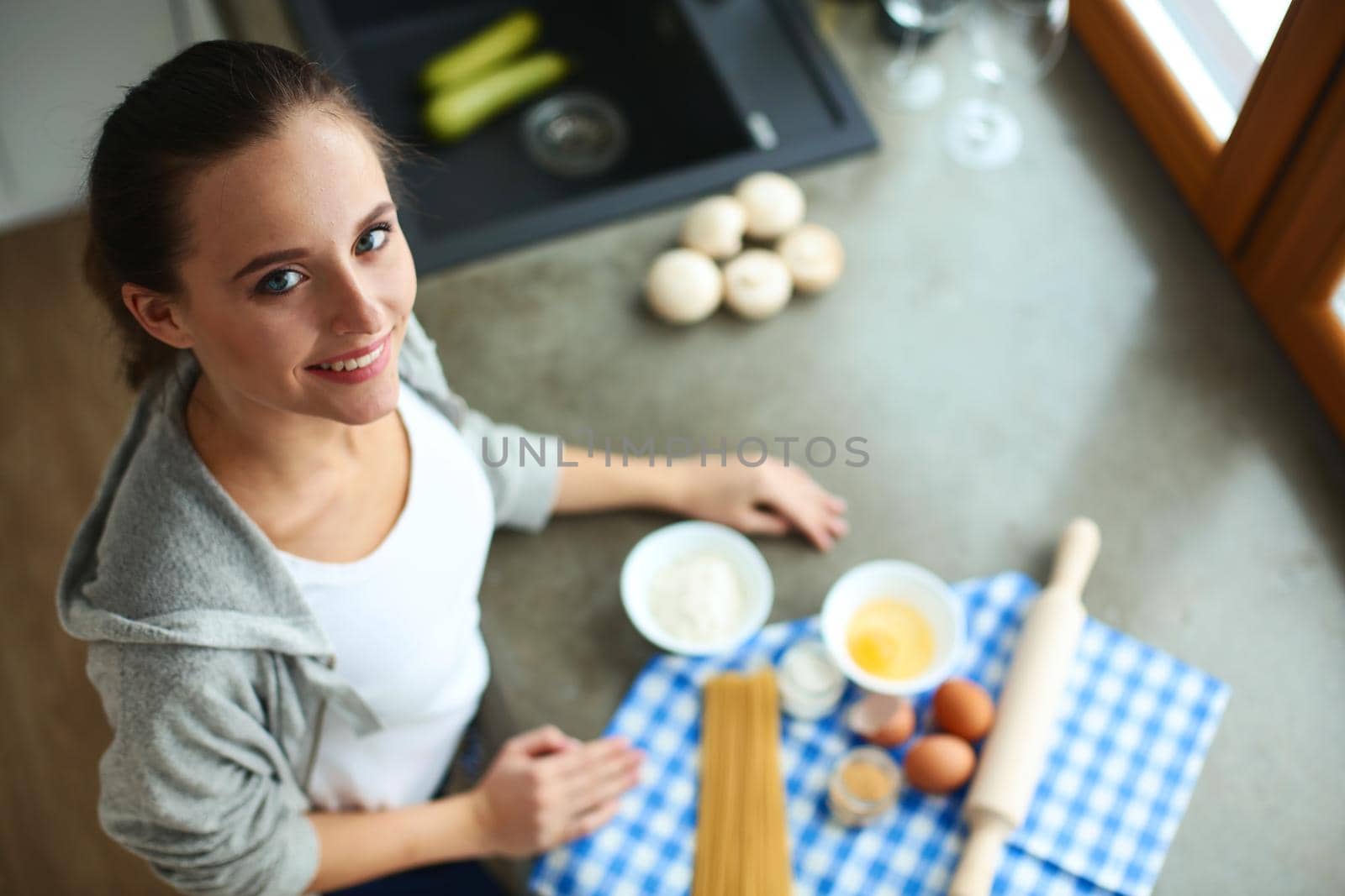 Beautiful woman cooking cake in kitchen standing near desk by lenetstan