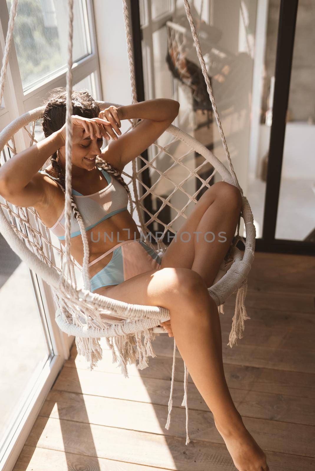 Young woman in underwear at hanging chair at room. Close view