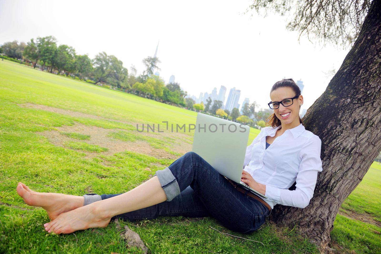 happy young student woman with laptop in city park study