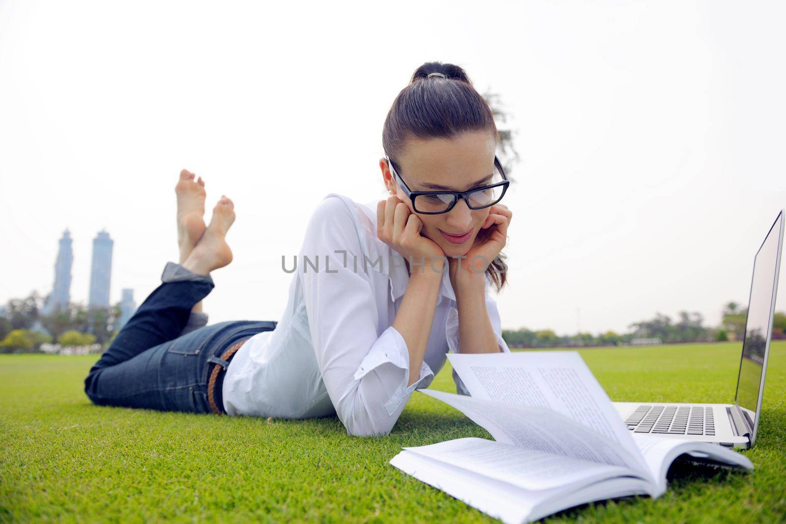 happy young student woman with laptop in city park study