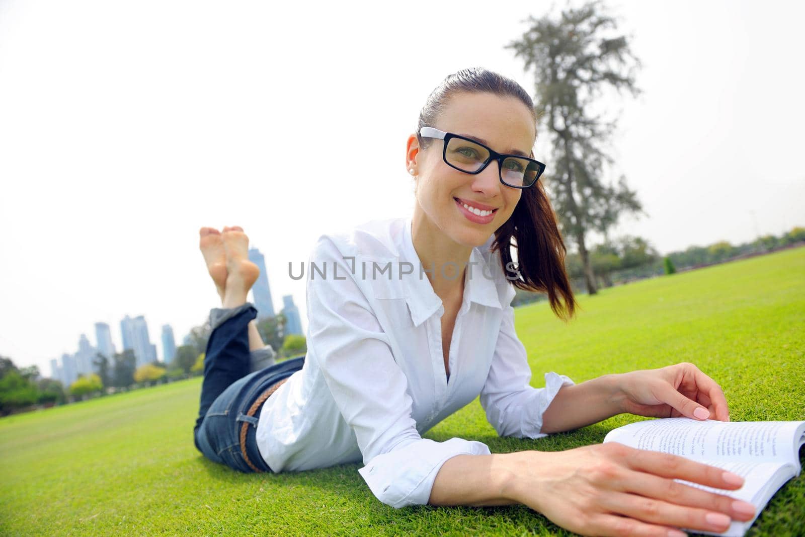 Young woman reading a book in the park by dotshock