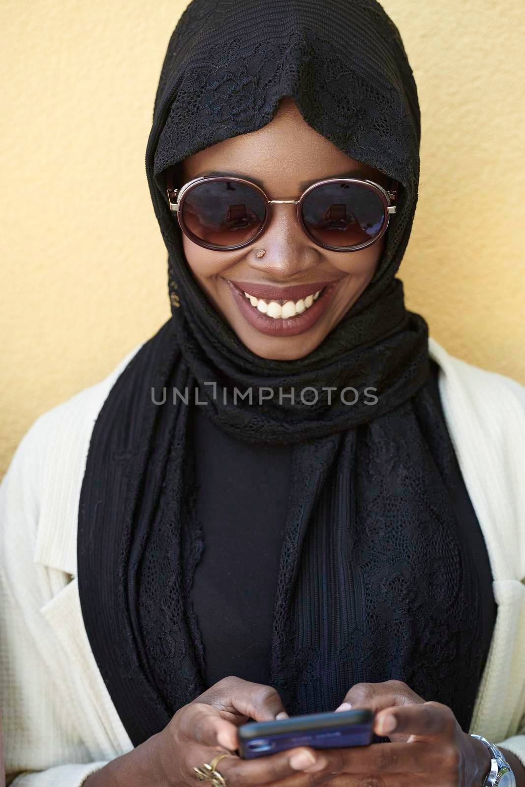 african  woman using smartphone wearing traditional islamic clothes by dotshock