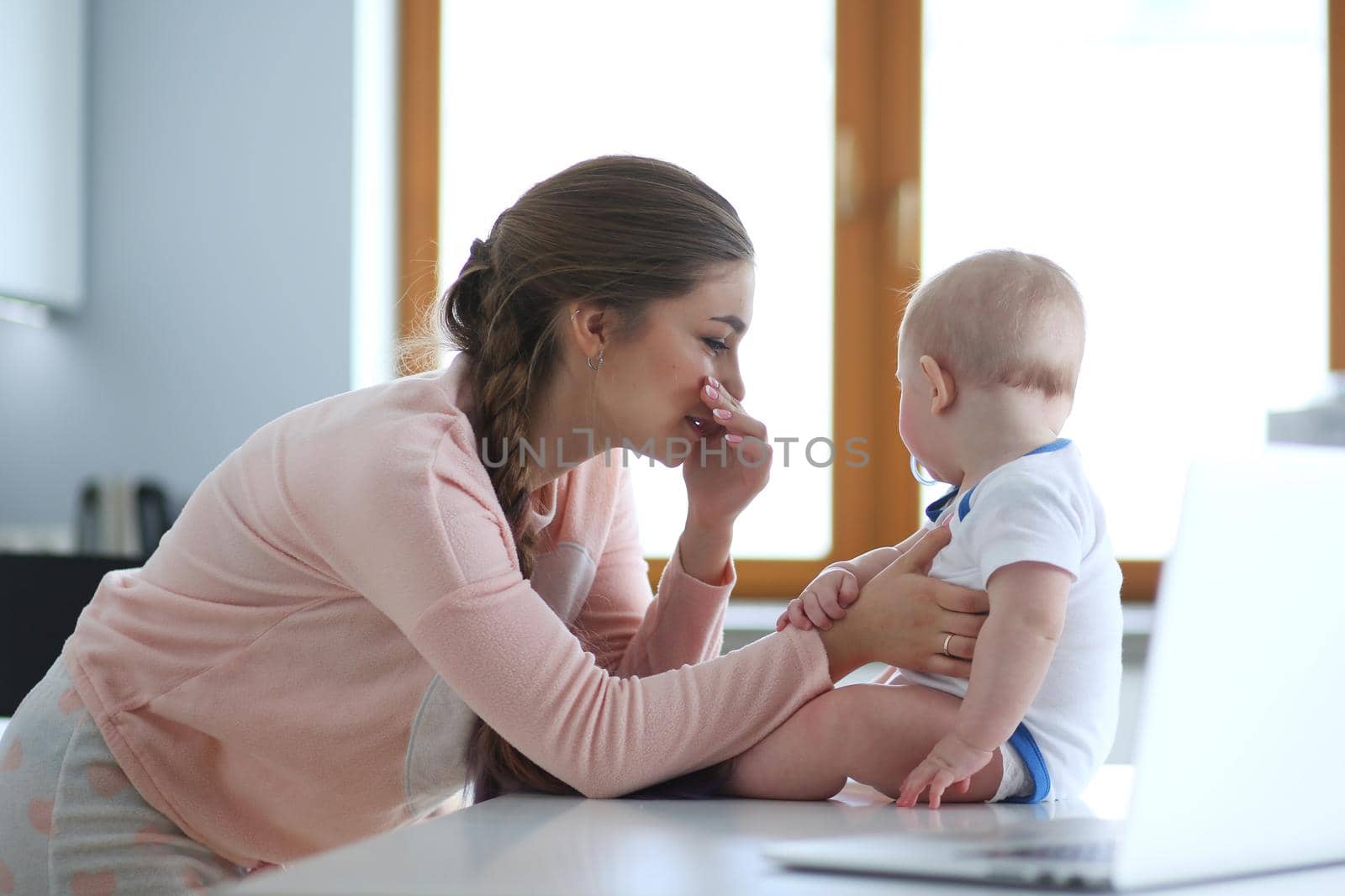 Mother with her baby in the bright kitchen at home