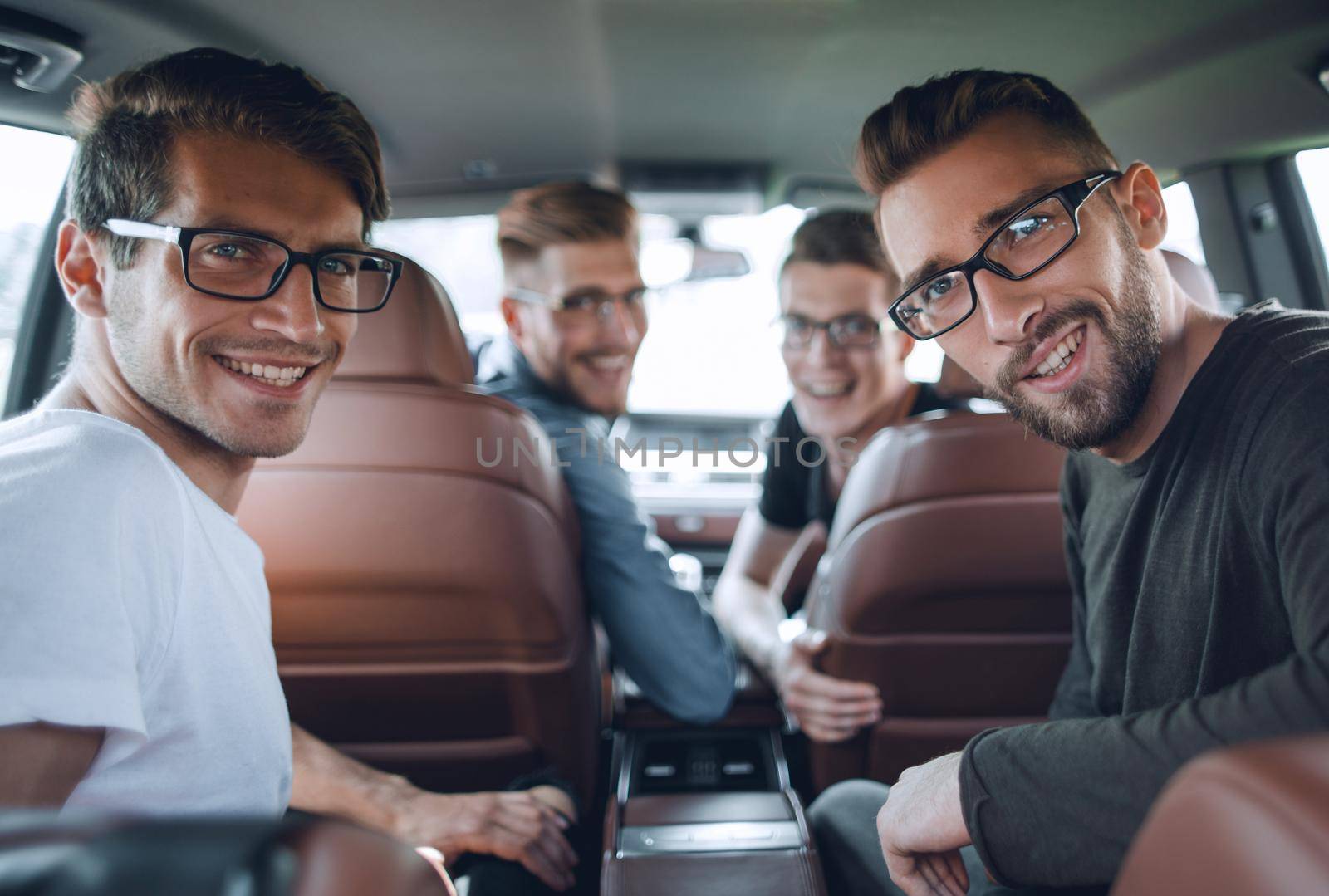 Handsome young man with friends in blue shirt driving car