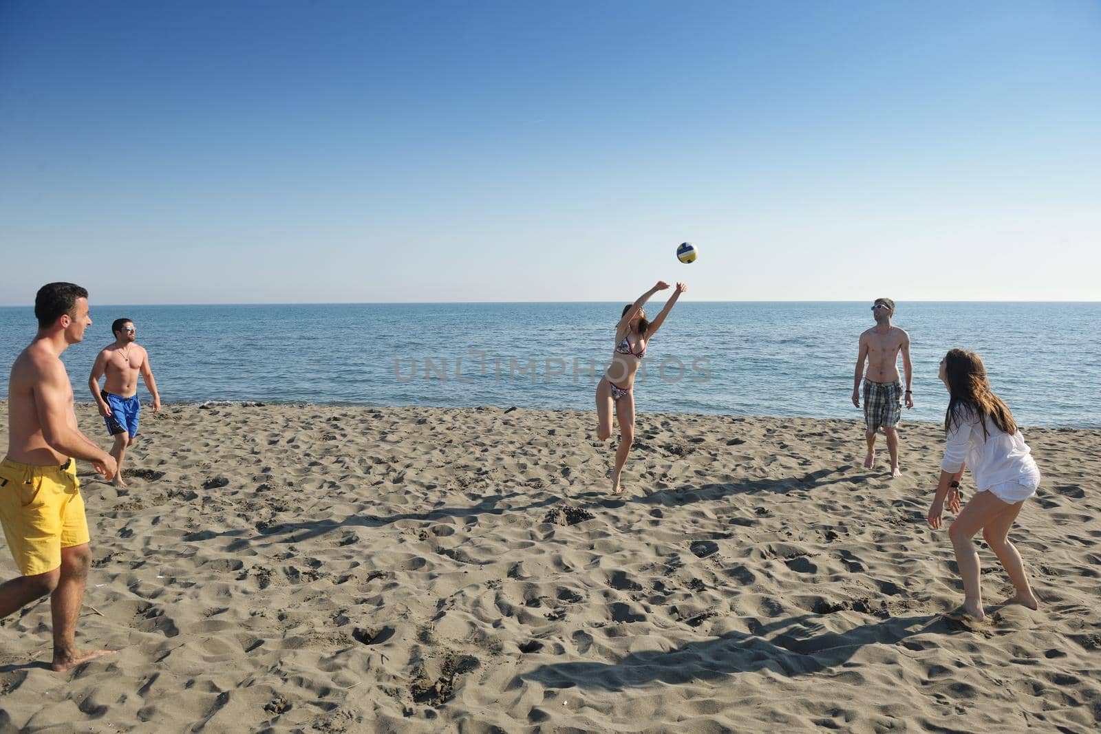 young people group have fun and play beach volleyball at sunny summer day