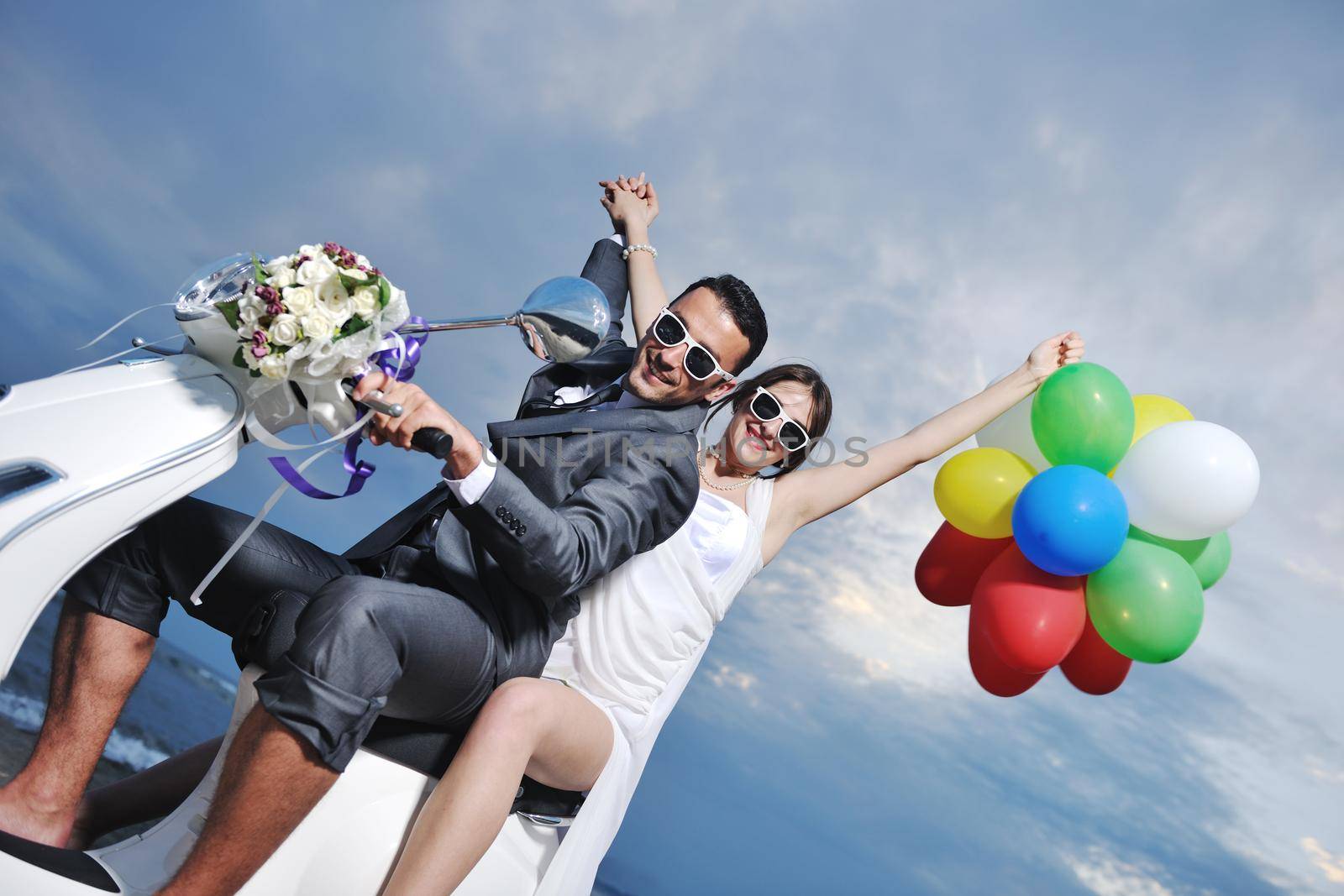 just married couple on the beach ride white scooter by dotshock