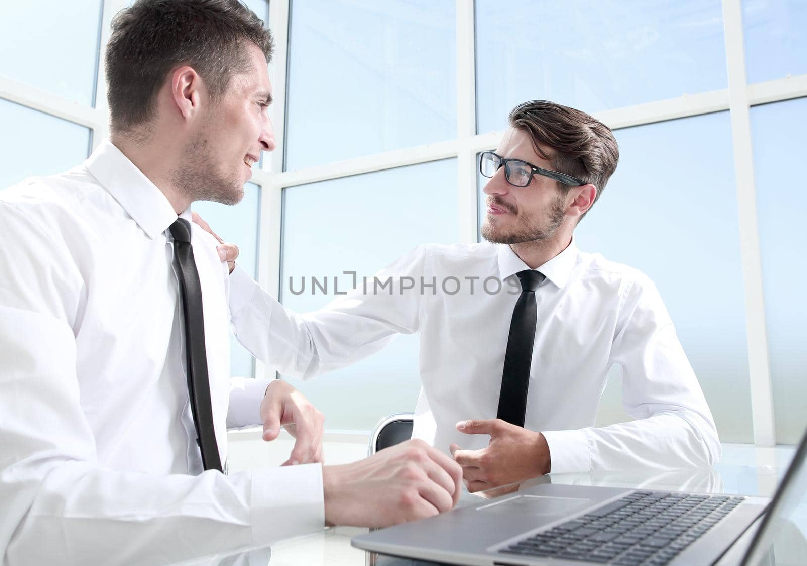 Two businessmen are sitting in the office and discussing the conclusion of a new deal