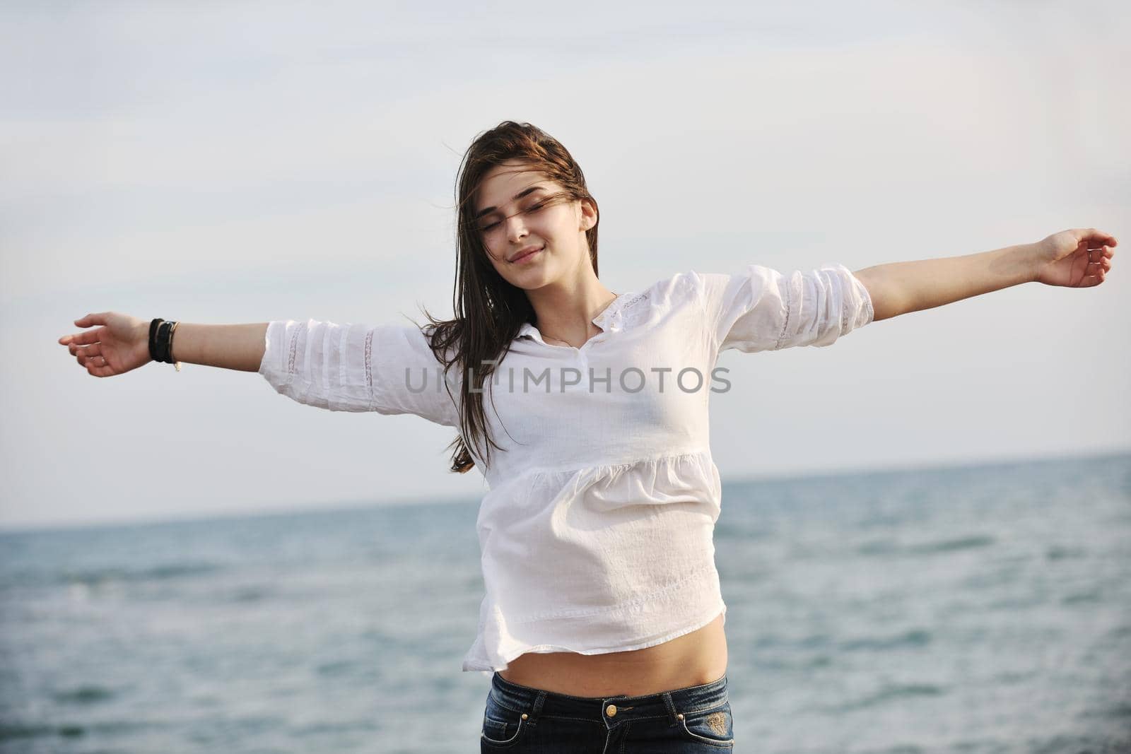 happy young woman relax on beautiful  beach at fresh summer morning and enjoy first ray of sun