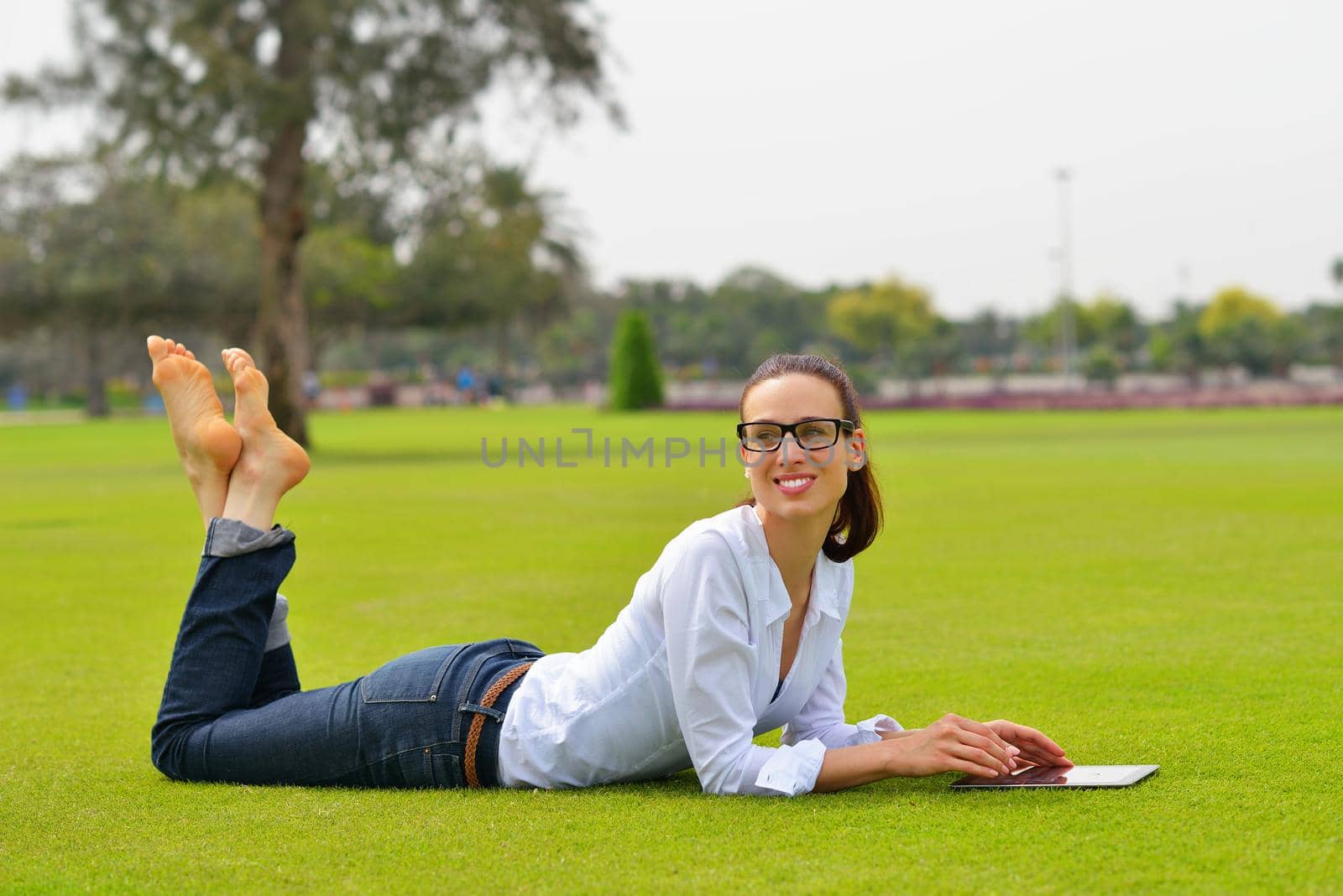 Beautiful young woman with  tablet in park by dotshock