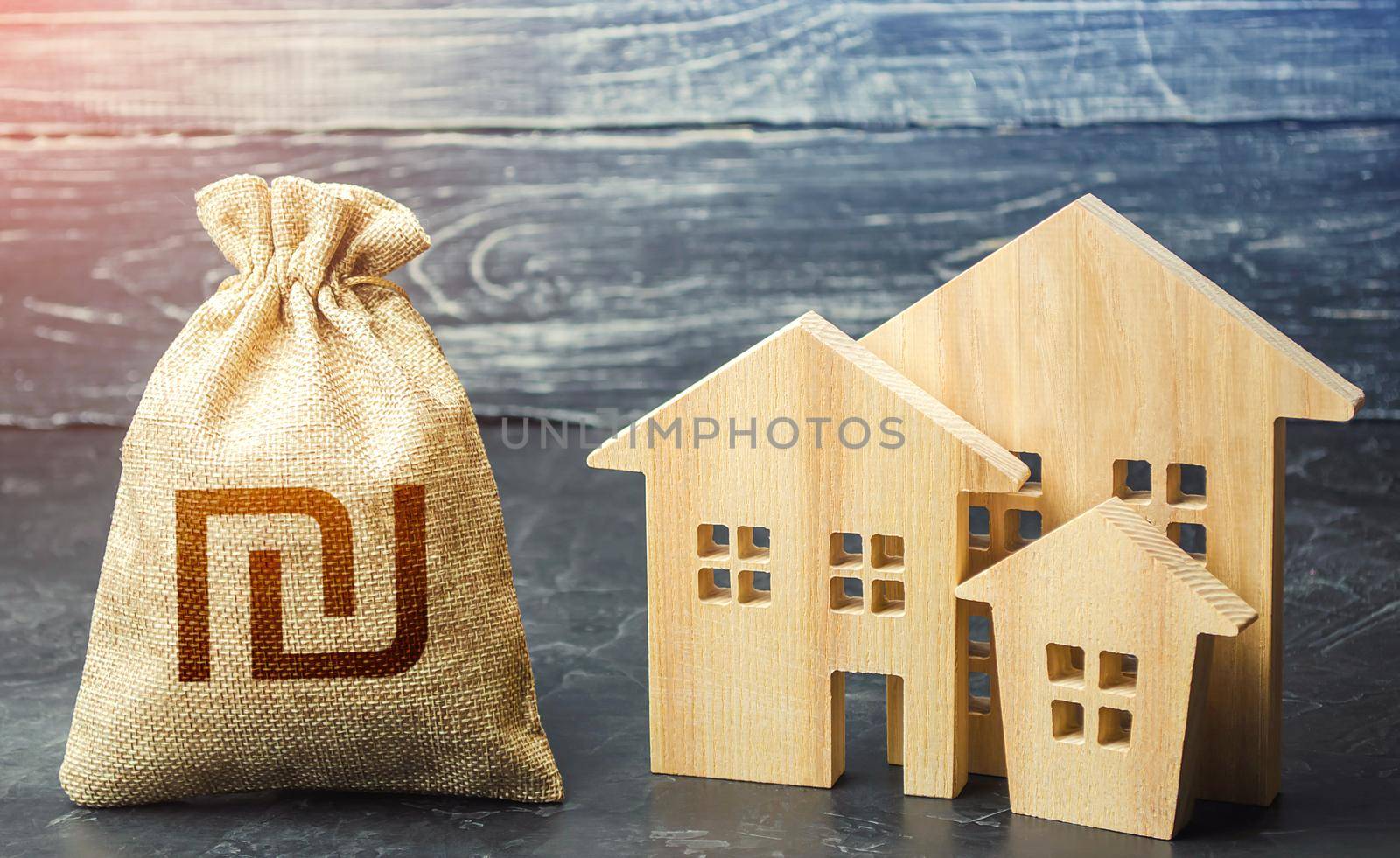 Israeli shekel money bag and figurines of residential buildings. Property tax. Financing urban development and infrastructure projects. Municipal budgeting. Increase investment attractiveness by iLixe48