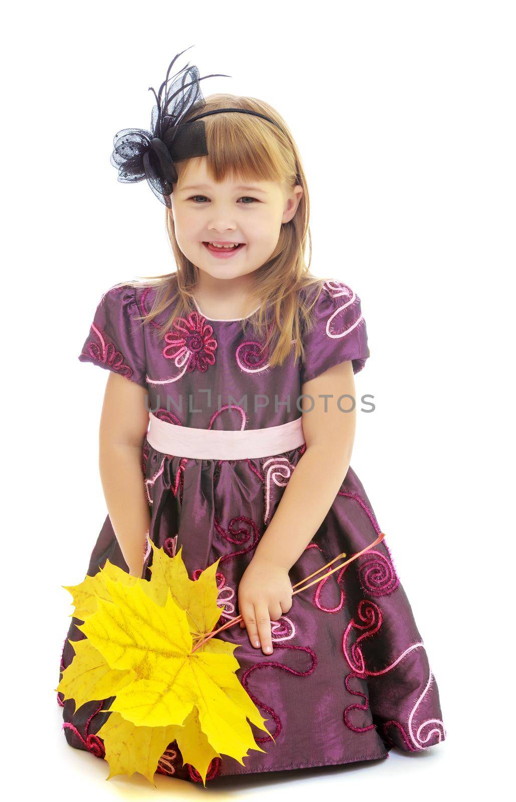 Nice little girl dressed in brown dress. She is holding a bouquet of maple leaves.Isolated on white background.