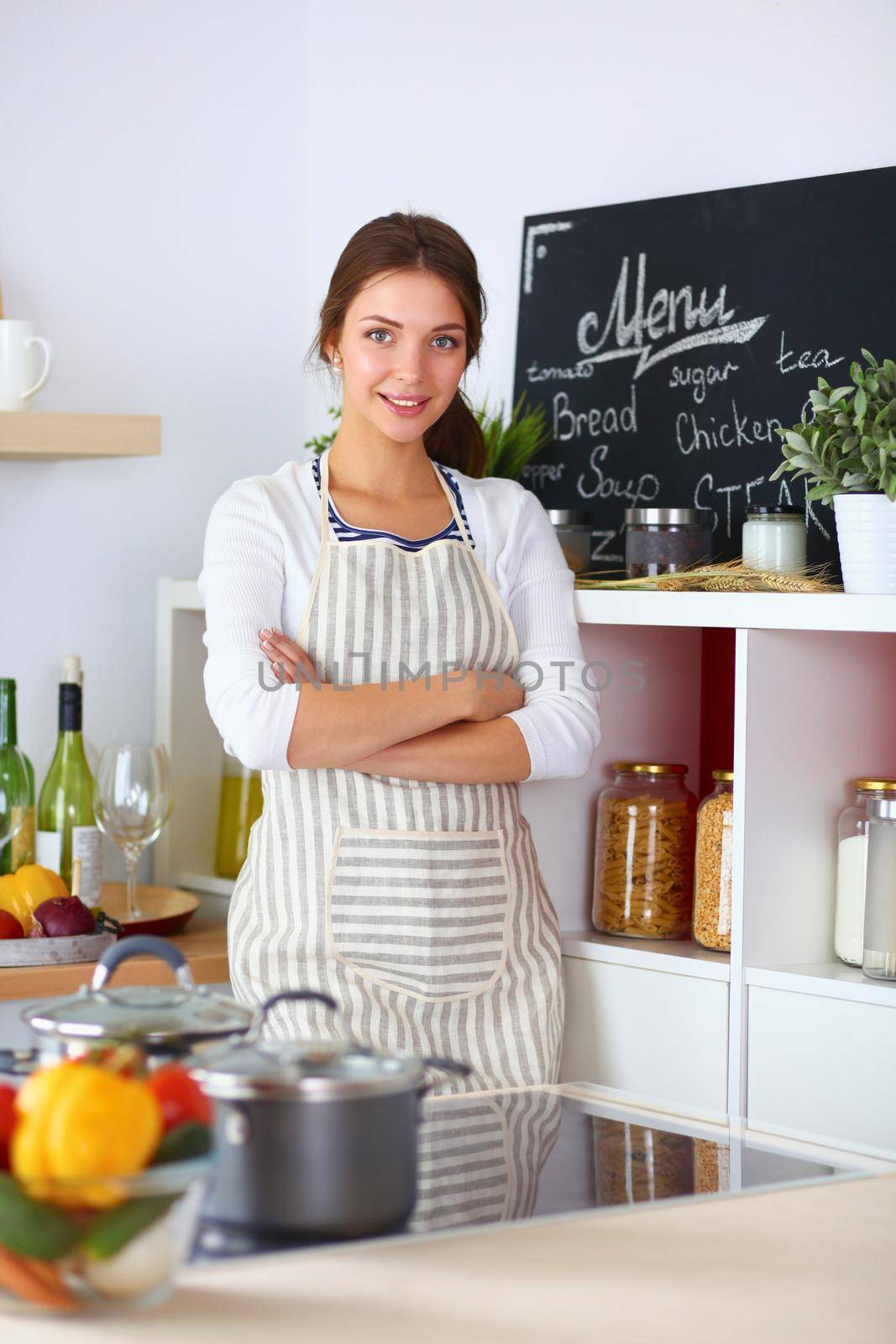 Young woman standing near desk in the kitchen.