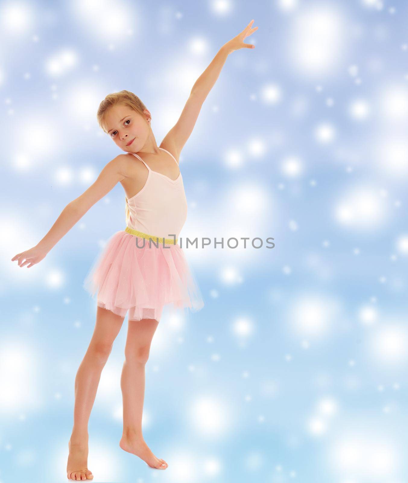 Charming little girl ballerina in a pink translucent dress.On a blue background with large, white, Christmas or new year's snowflakes.