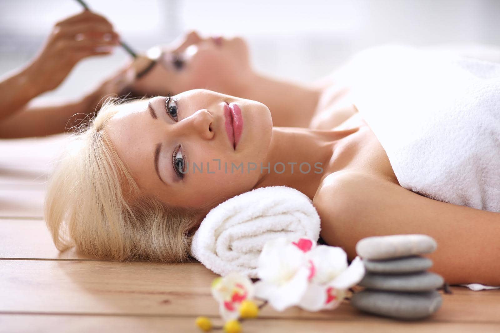 Two young beautiful women relaxing and enjoying at the spa center by lenetstan