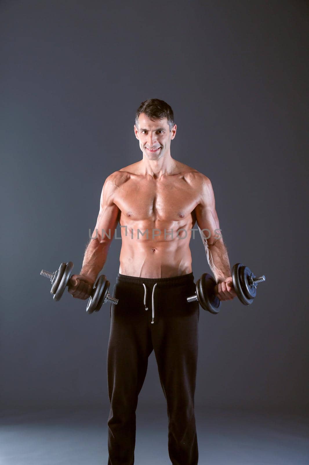 Handsome muscular man working out with dumbbells. Personal fitness instructor. Personal training. by lenetstan