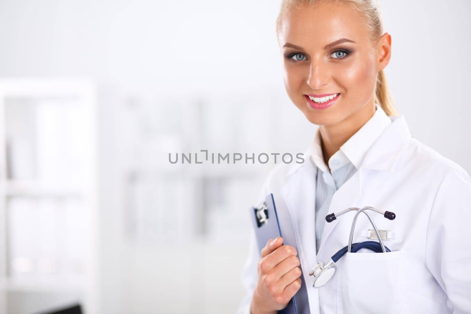 Smiling female doctor with a folder in uniform standing