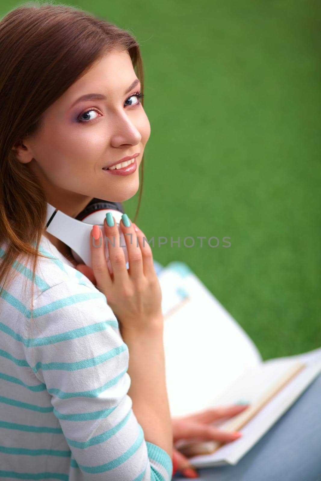 Woman listening to the music sitting on grass.