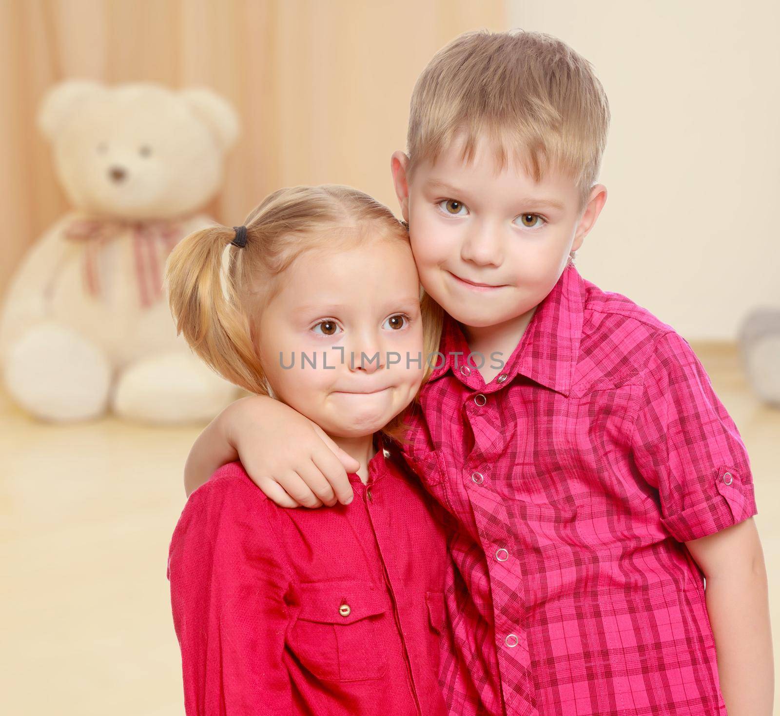 The concept of preschool development of the child ,against a child's room where in the background a Teddy bear.Little brother and sister cute hug.