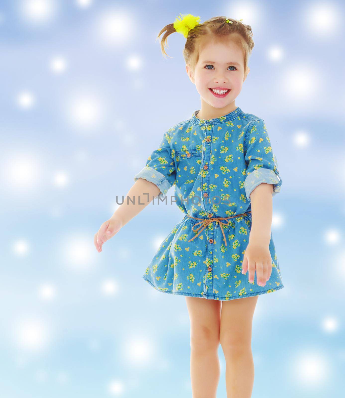 Laughing little girl in a short summer dress. Gentle blue Christmas background with white snowflakes abstract.