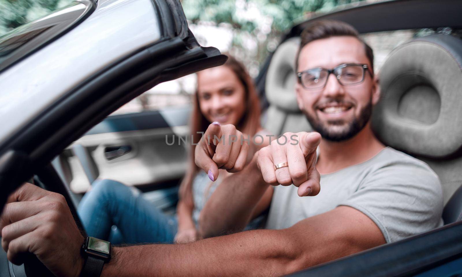 loving couple in a convertible car pointing at you.the concept of choice