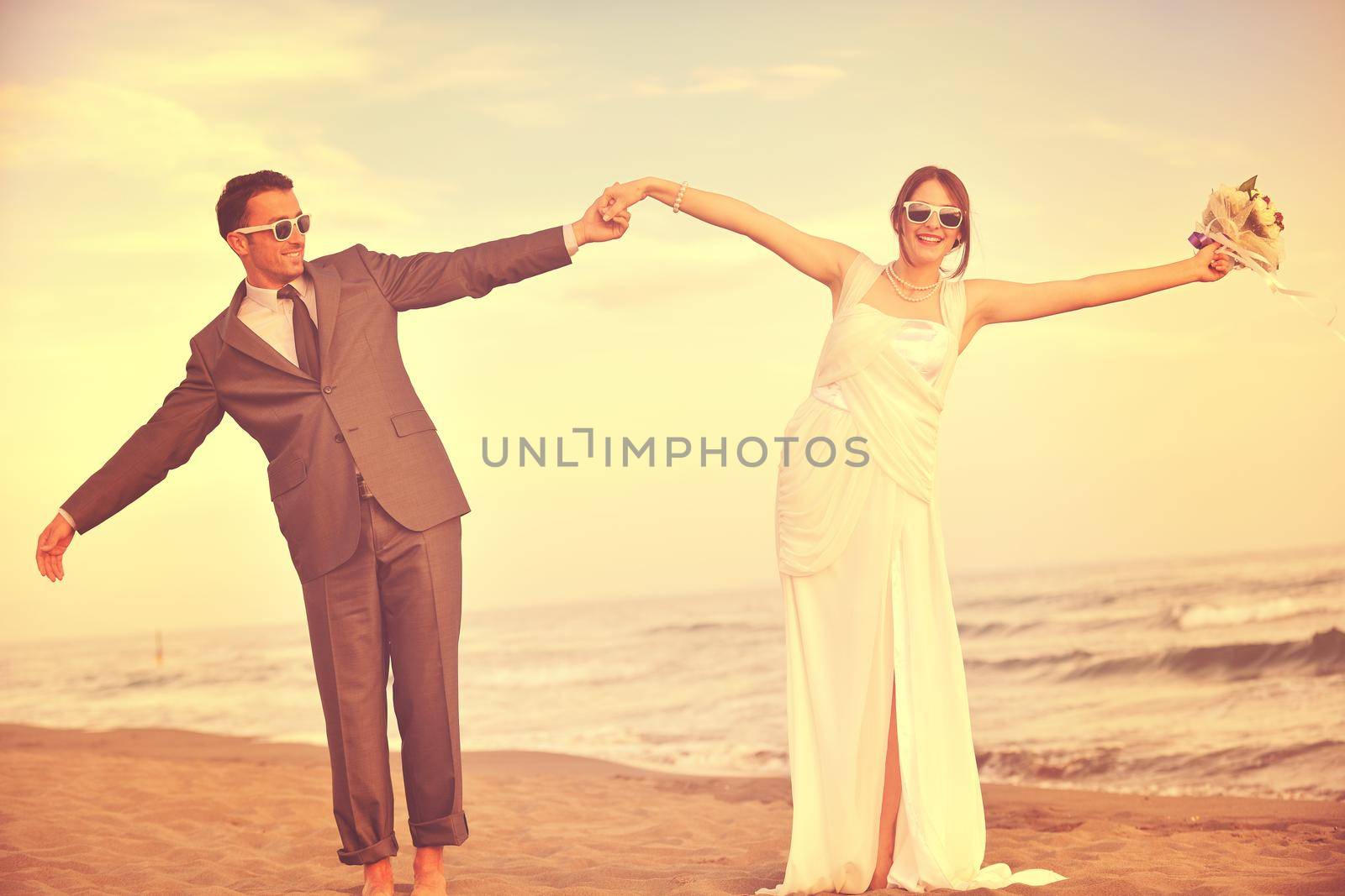 happy just married young couple celebrating and have fun at beautiful beach sunset