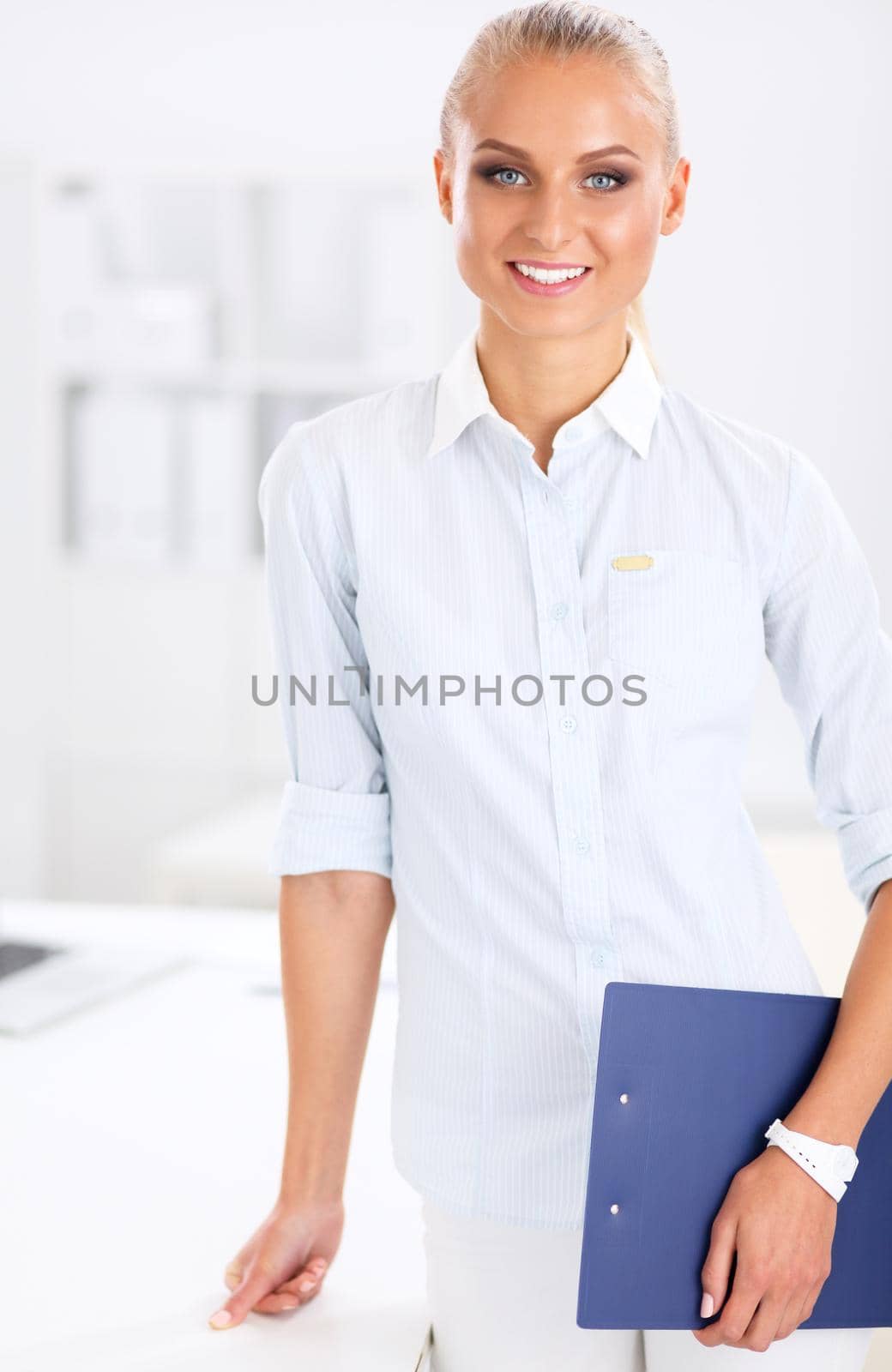 Young happy businesswoman in office holding folder