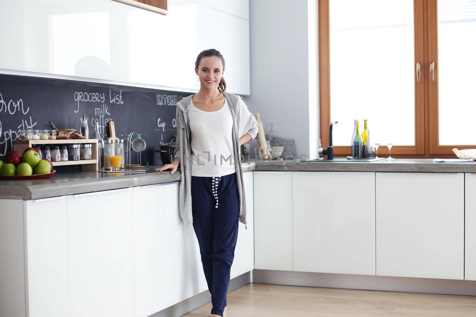 Young woman with orange juice and tablet in kitchen