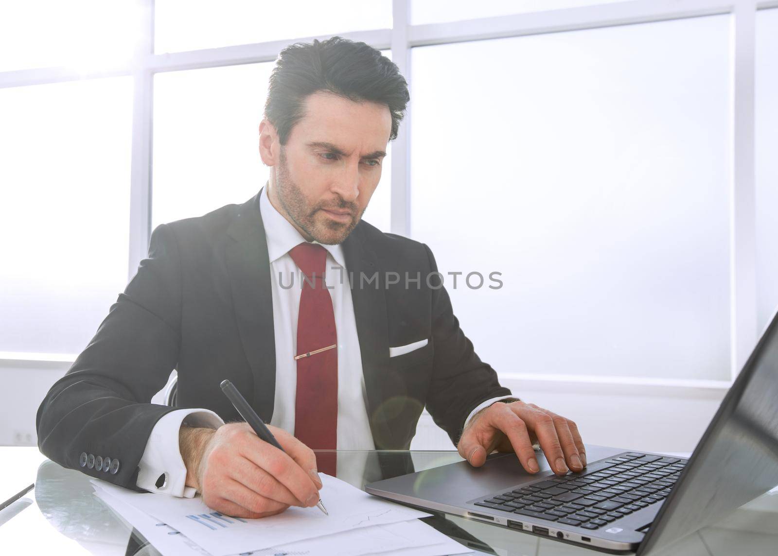 businessman uses a laptop to check financial data by asdf