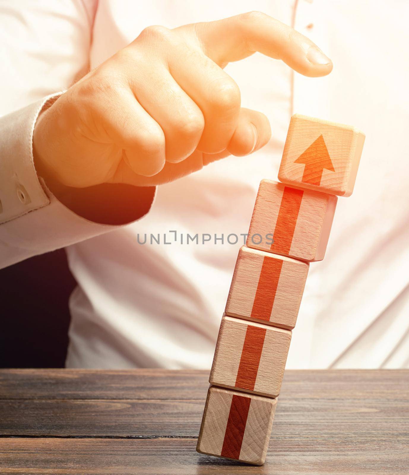 A man knocks down a tower of blocks with an up arrow. End of career, destruction of progress and achievements. Sabotage. Eliminate the phenomenon, prevent further growth. Disruption business processes by iLixe48