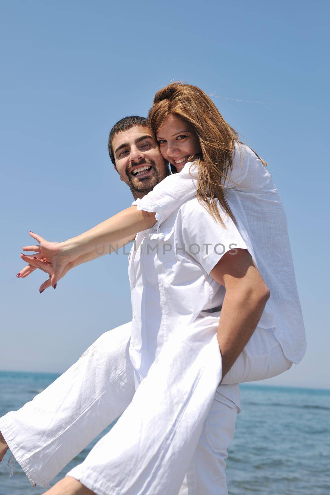 happy young couple have fun on beach by dotshock