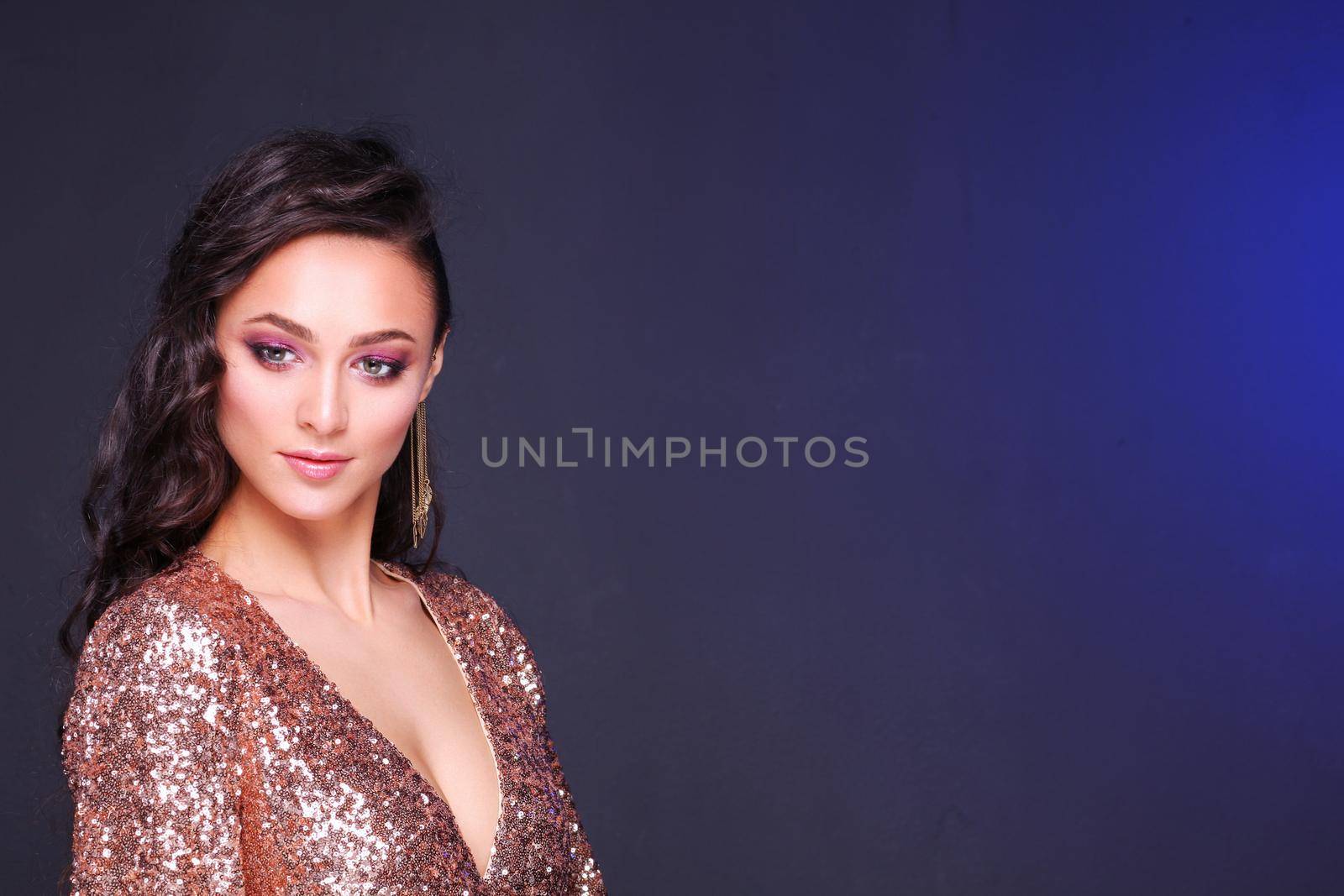 Beautiful young woman in evening dress on black background