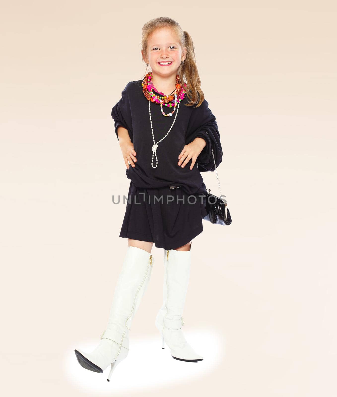 Fashionable little girl in a black dress and long boots on high sole.