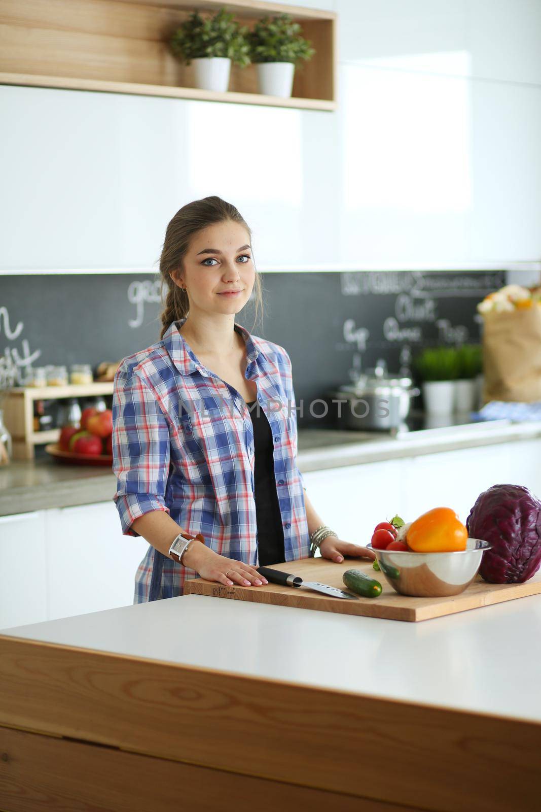 Young woman cutting vegetables in kitchen near desk.