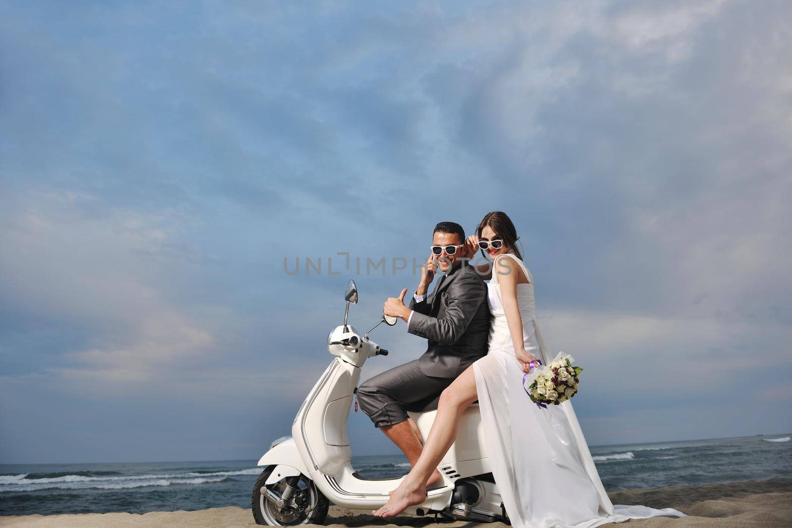 just married couple on the beach ride white scooter by dotshock