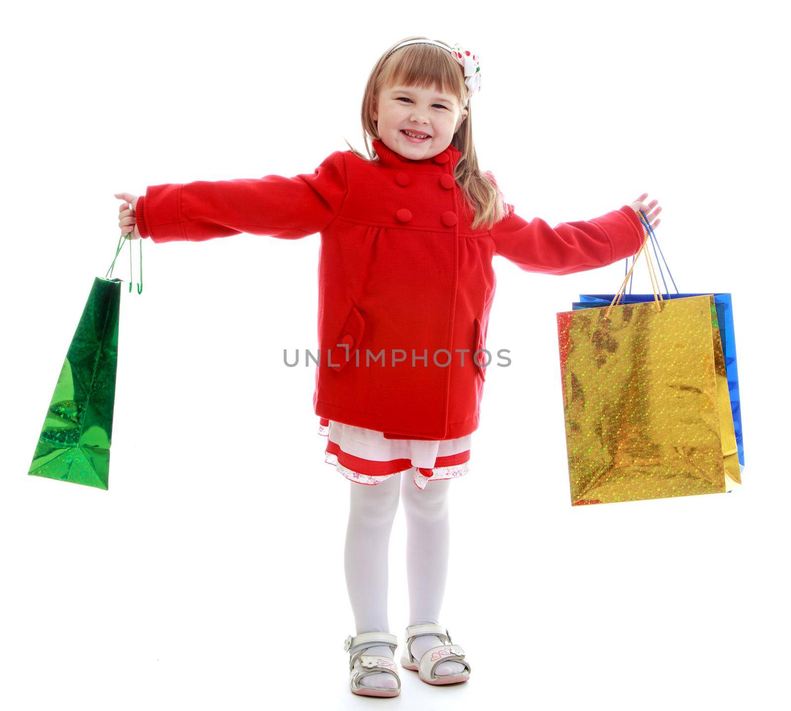 Charming little girl waving colorful shopping bags. Happy childhood, fashion, autumnal mood concept. Isolated on white background