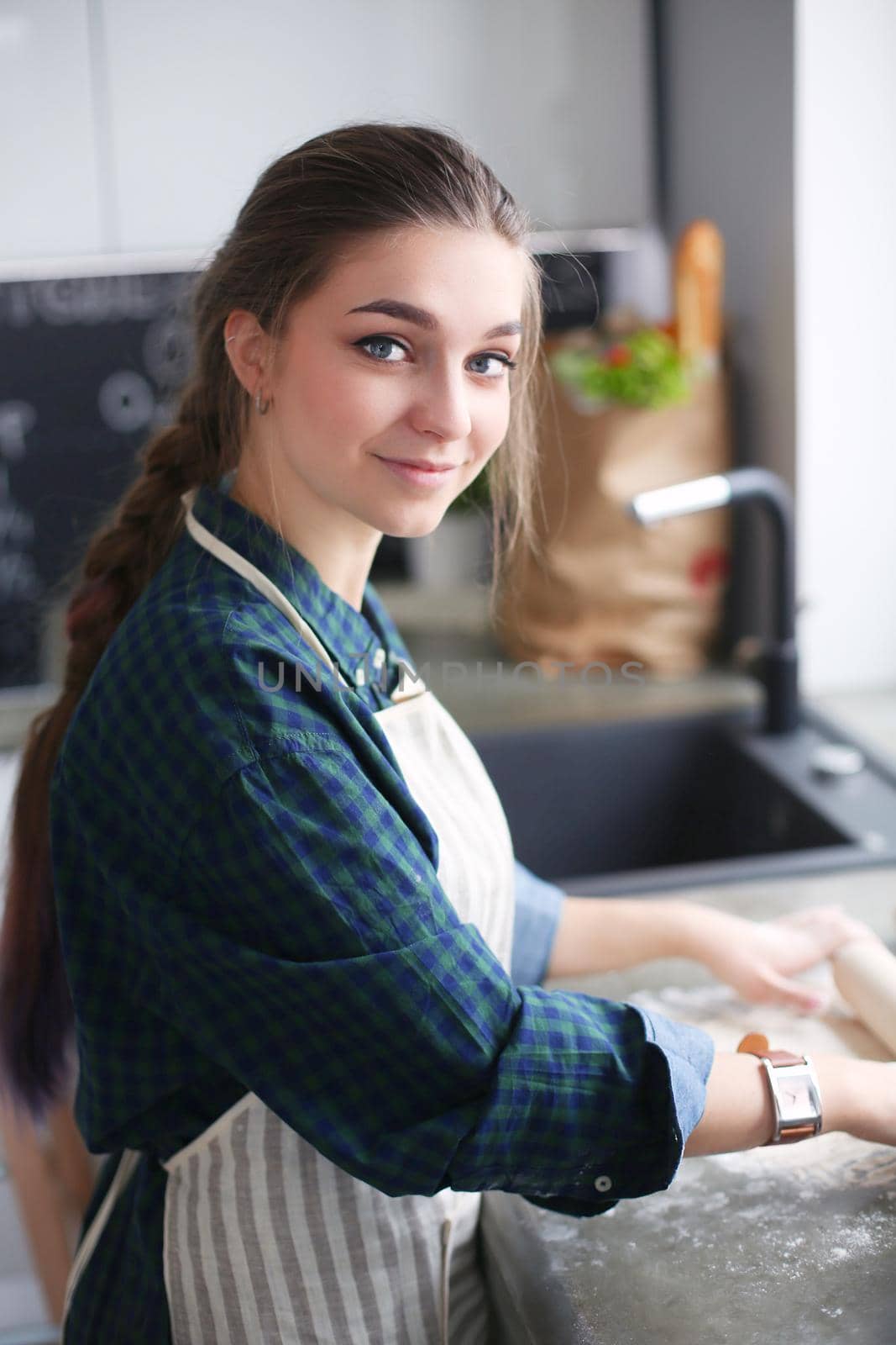 Beautiful woman cooking cake in kitchen standing near desk