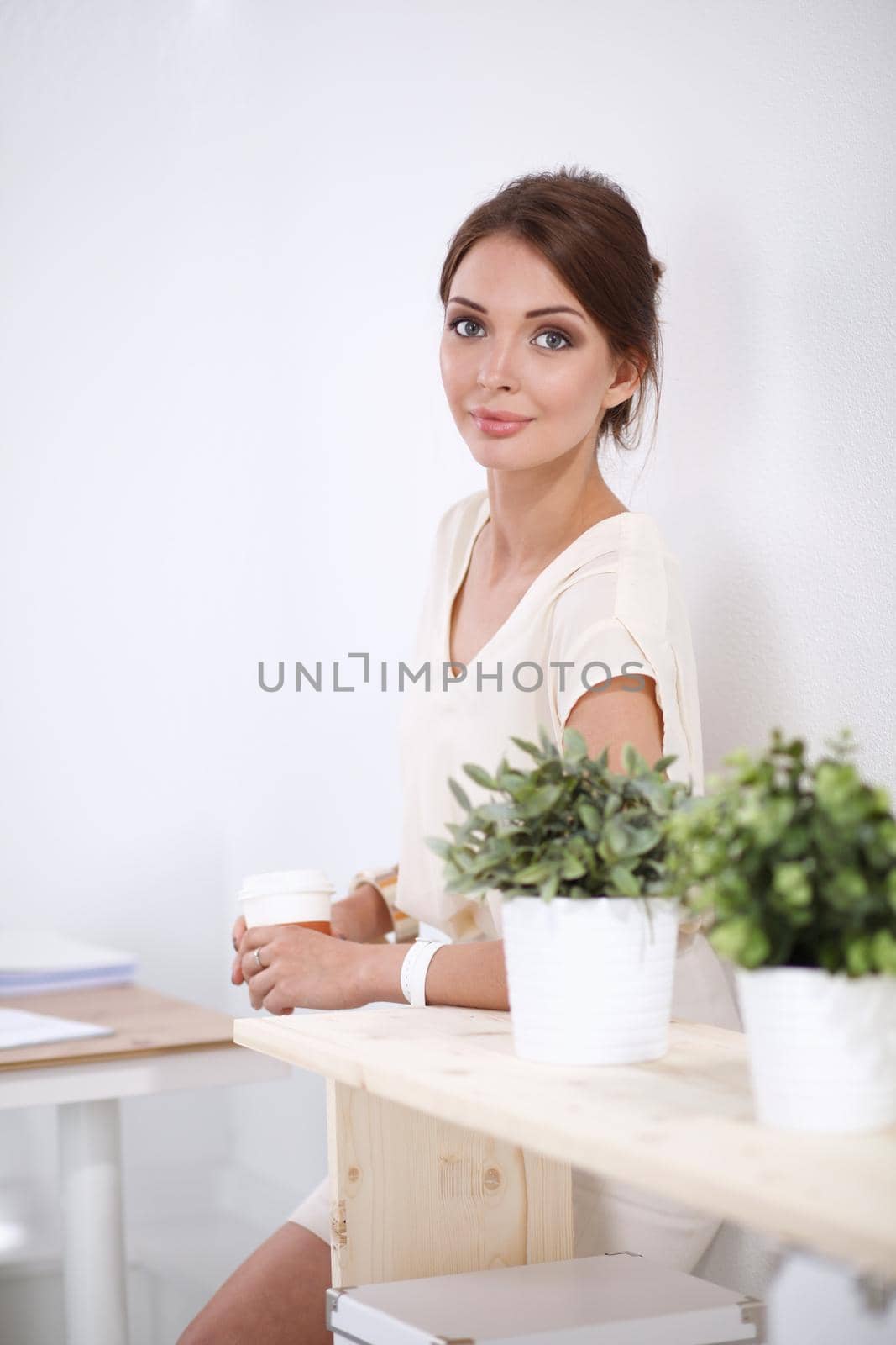 Attractive young businesswoman standing near desk in the office by lenetstan