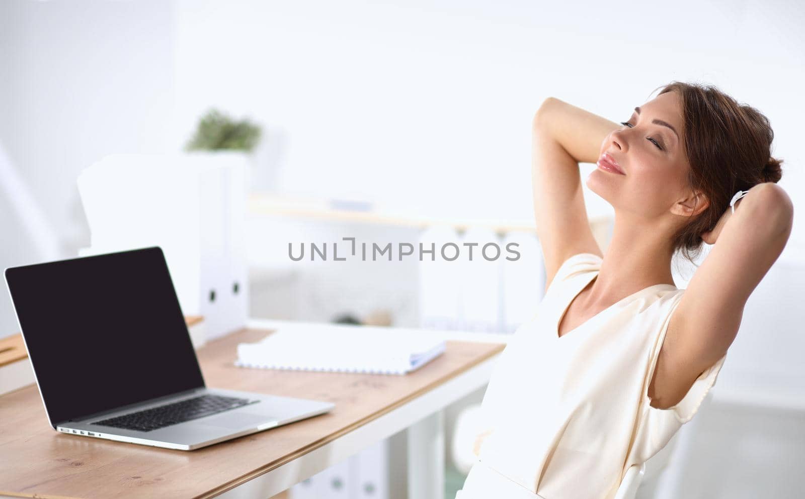 Business woman relaxing with her hands behind her head and sitting on a chair