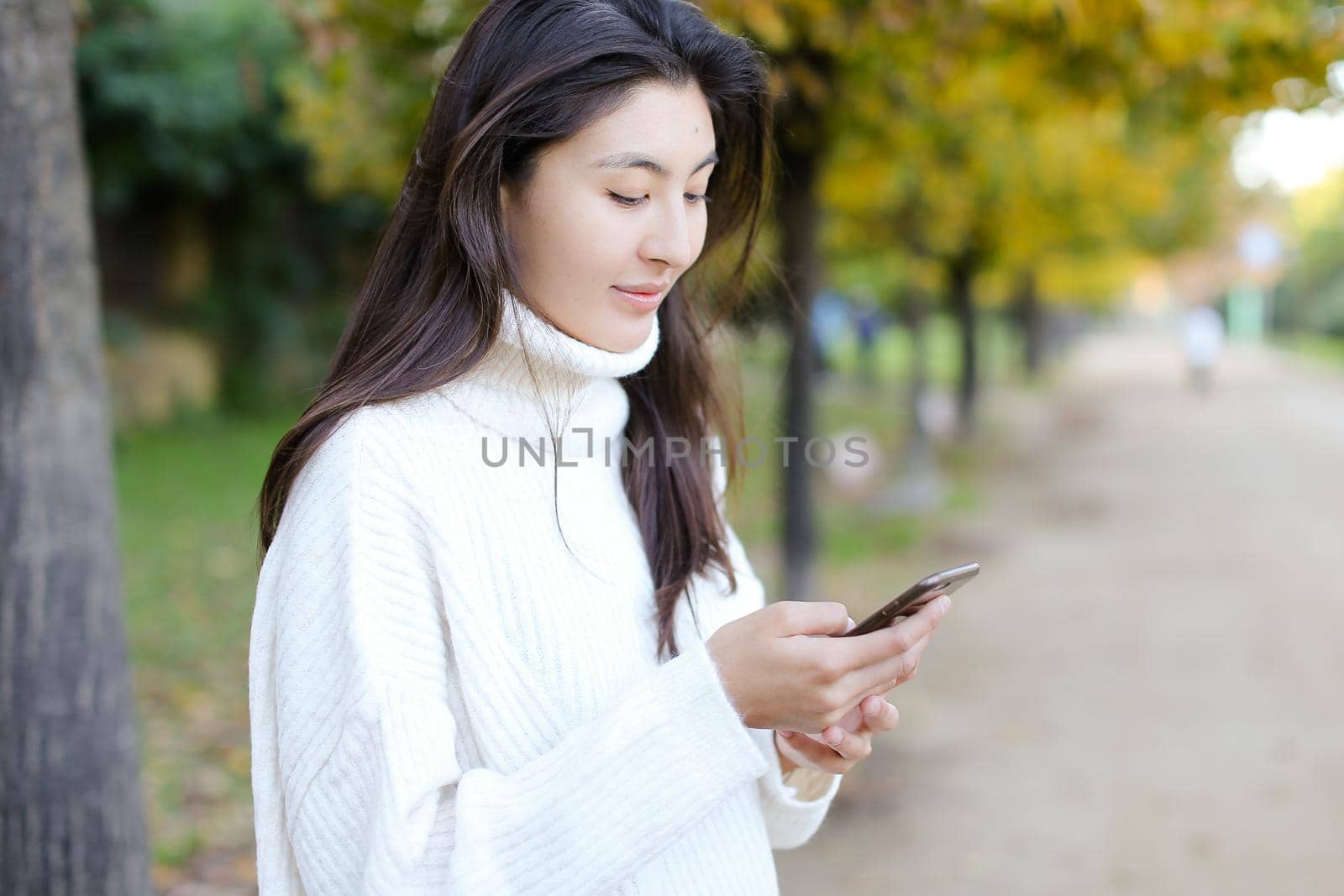 Korean girl using smartphone and walking in park. by sisterspro