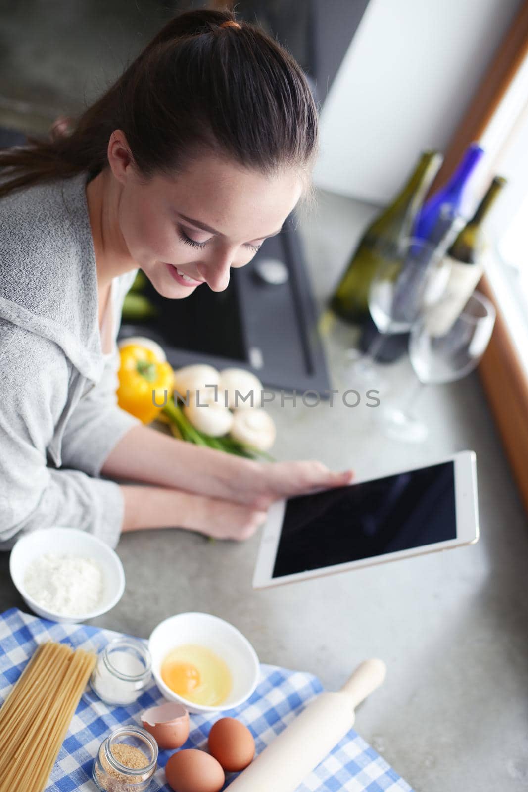 Beautiful woman cooking cake in kitchen standing near desk