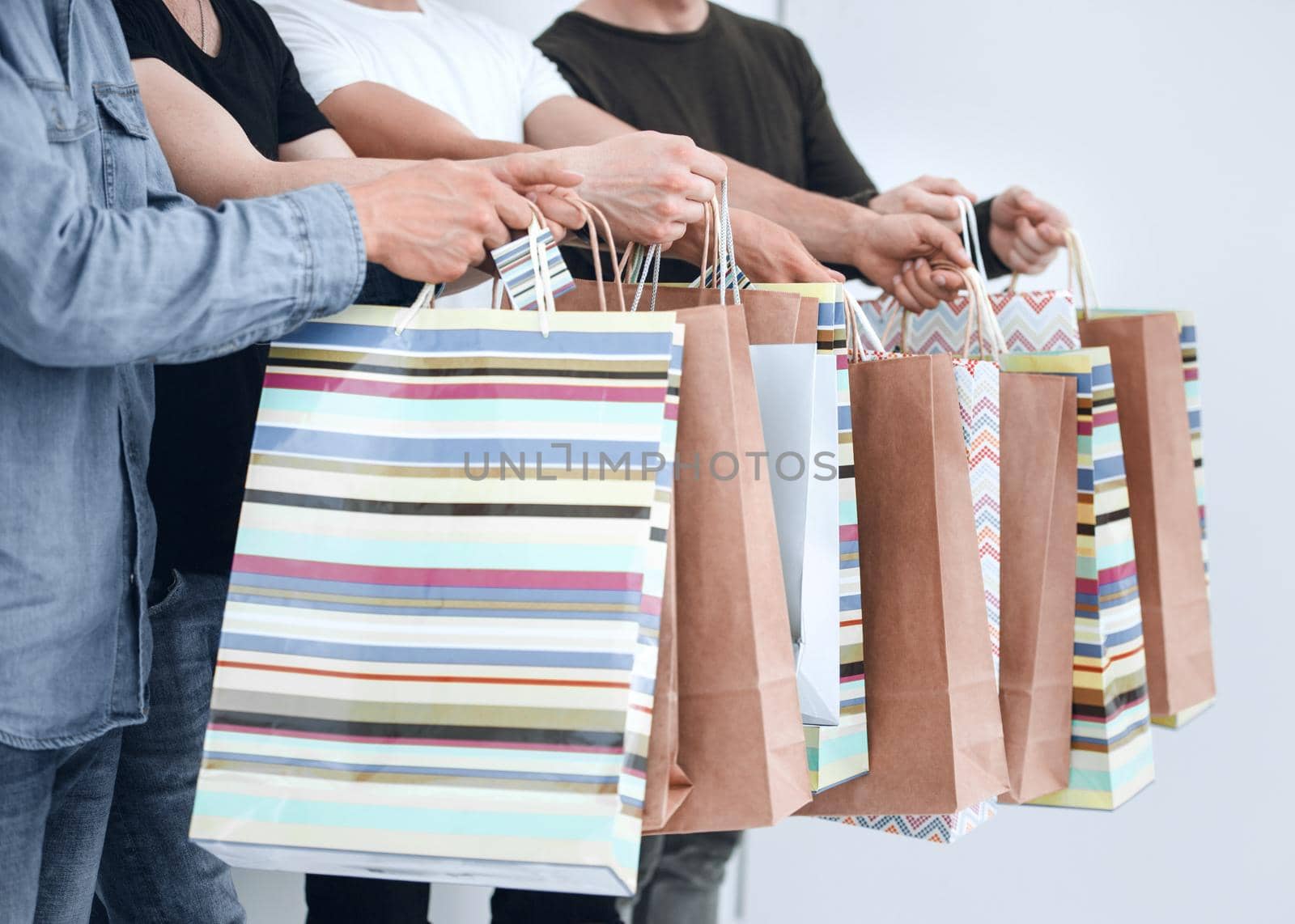 company of young people holding a shopping bag isolated on a gray background