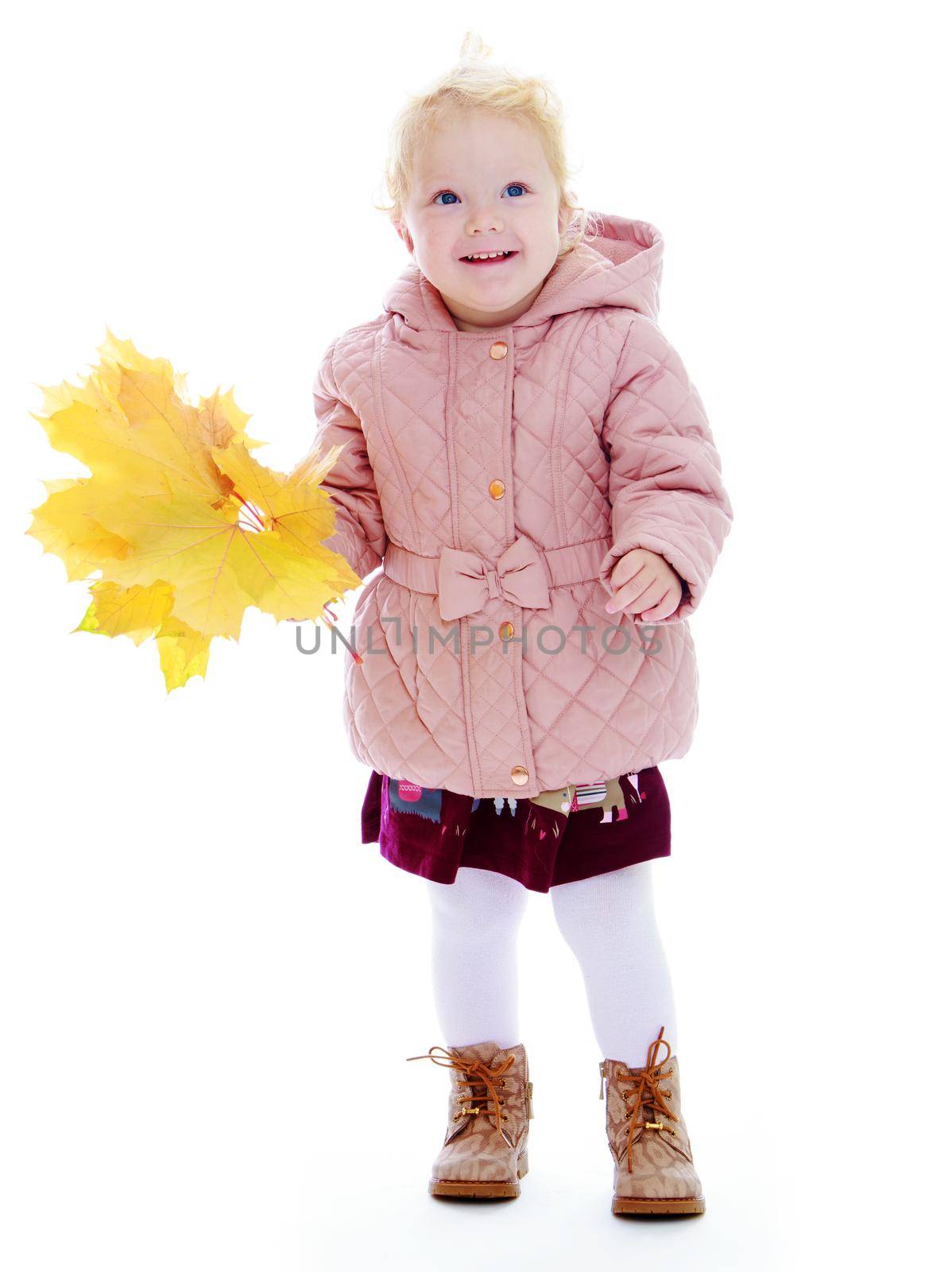Adorable little girl in autumn coat holding a maple leaf.