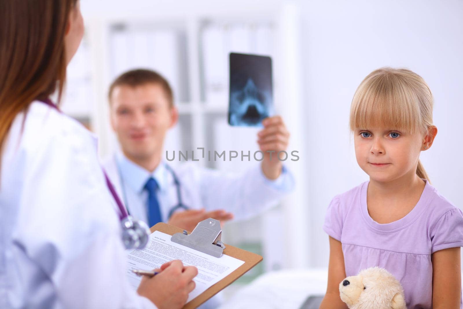 Female doctor examining child with stethoscope at surgery .