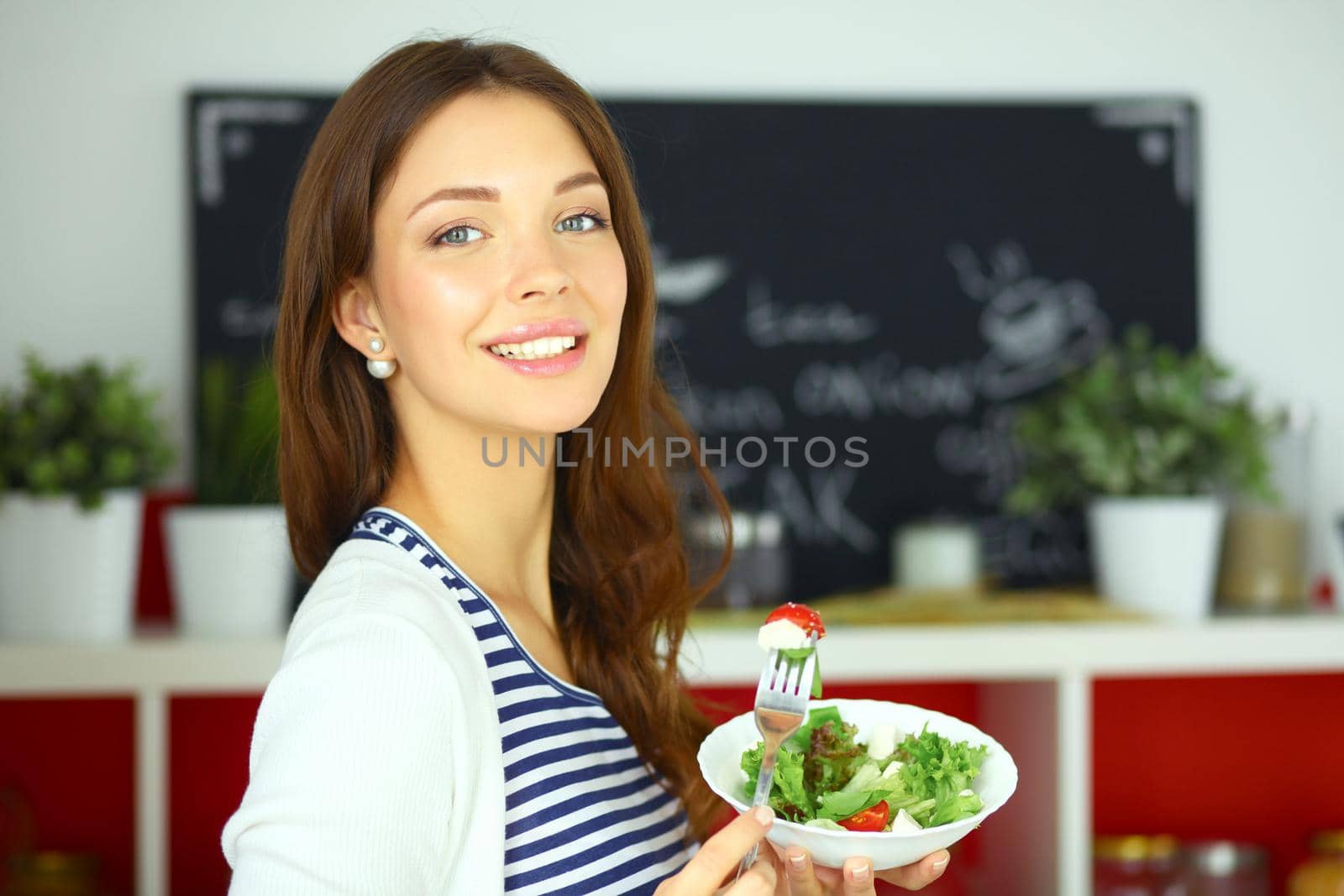 Young woman eating salad and holding a mixed .