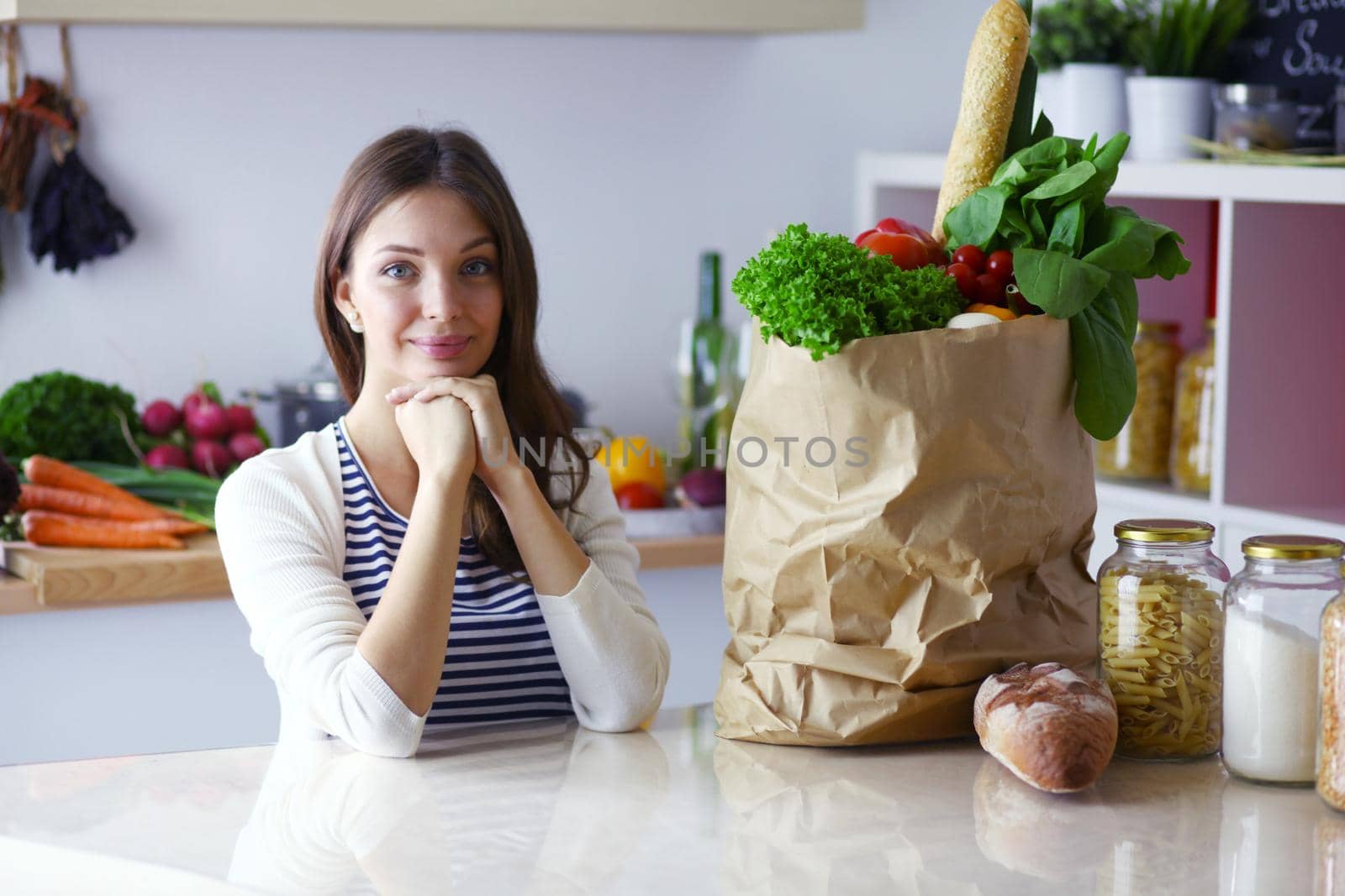 Young woman holding grocery shopping bag with vegetables .Standing in the kitchen. Young woman by lenetstan