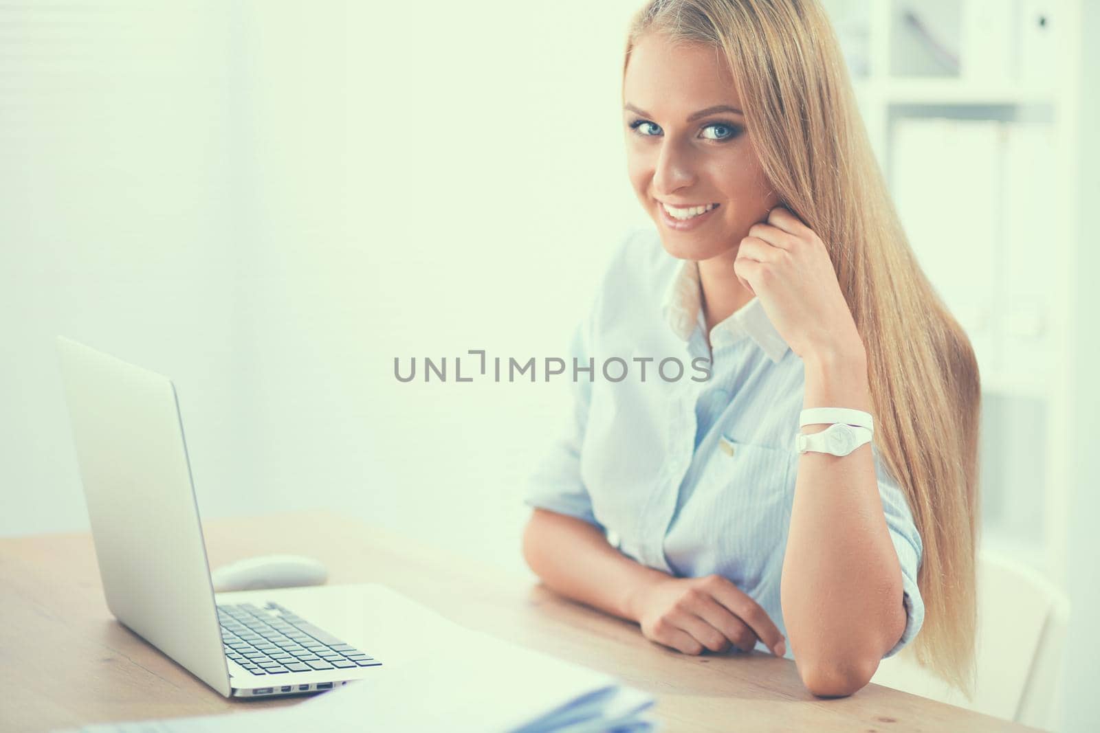 Attractive businesswoman sitting on a desk with laptop in the office by lenetstan