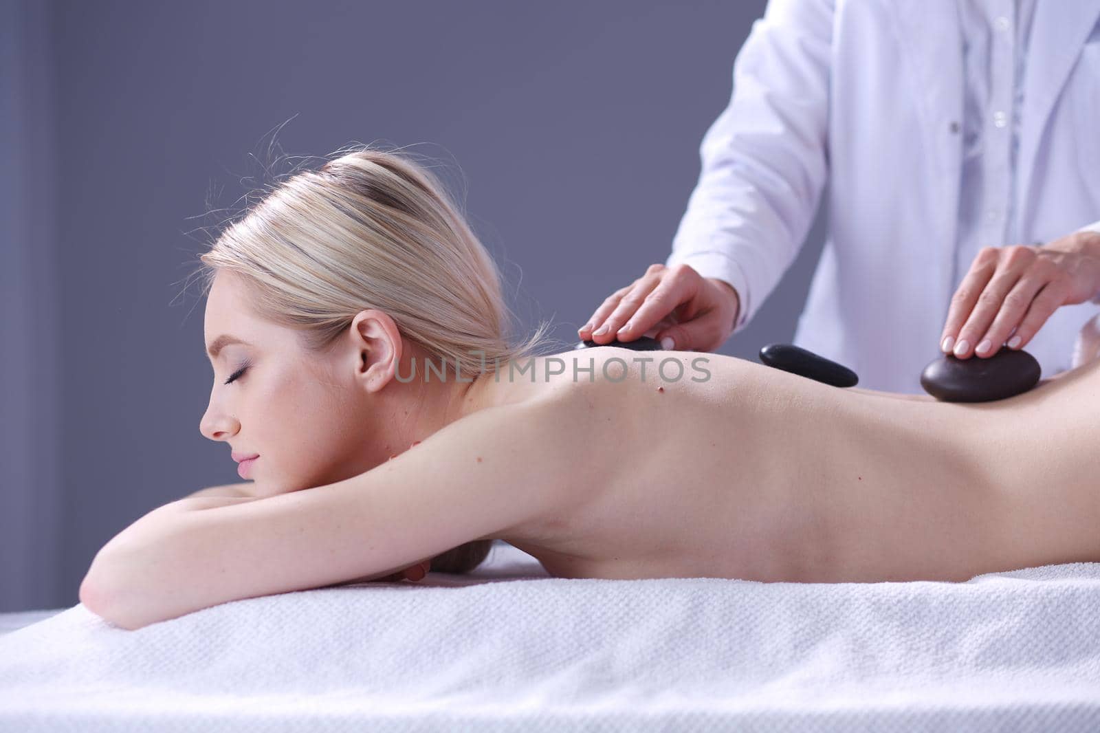 Young woman lying on a massage table,relaxing with eyes closed. Woman. Spa salon.