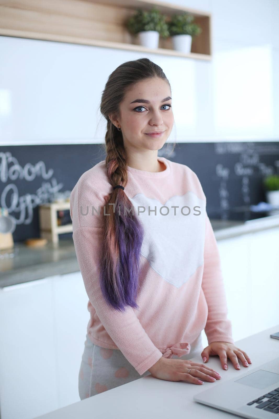 Woman using mobile phone standing in modern kitchen