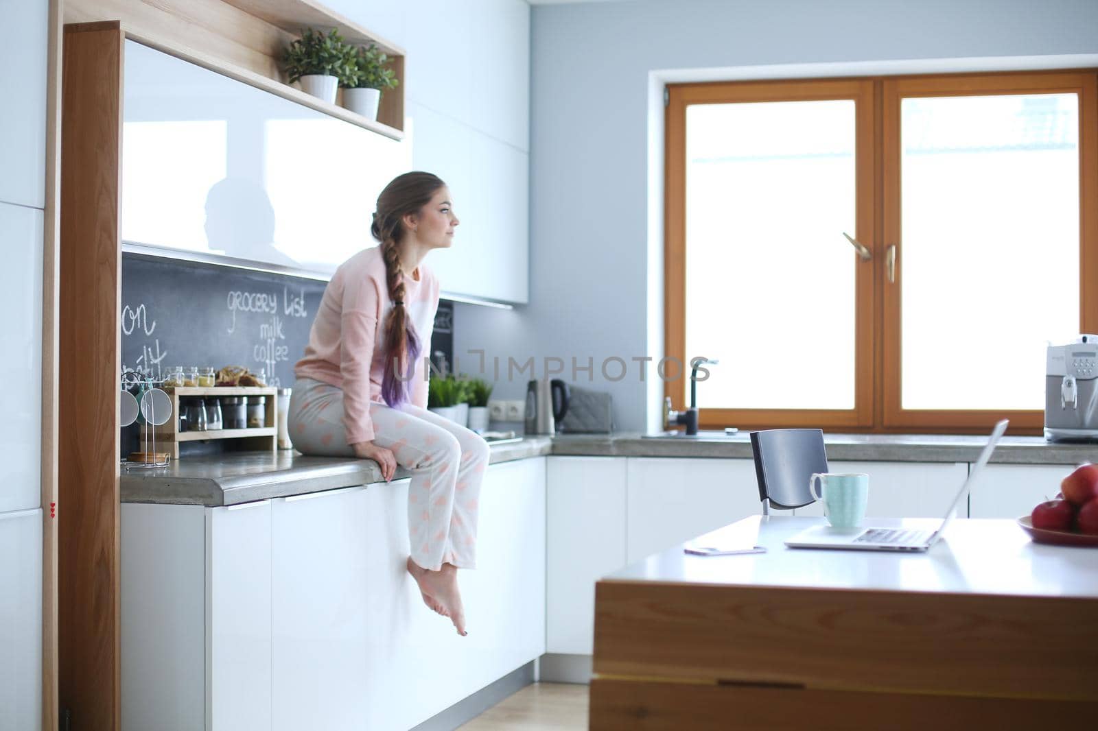 Young woman sitting on table in the kitchen